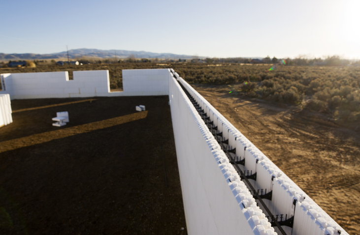 A partially completed ICF (Insulated Concrete Form) wall with reinforcing rebar inside. Part of a new house being constructed.